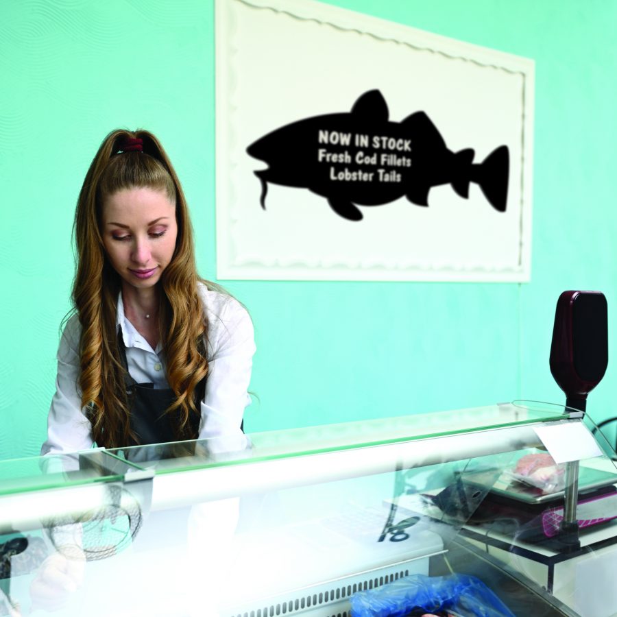 An fish shaped chalkboard hanging from a wall that can be written on with chalkpen
