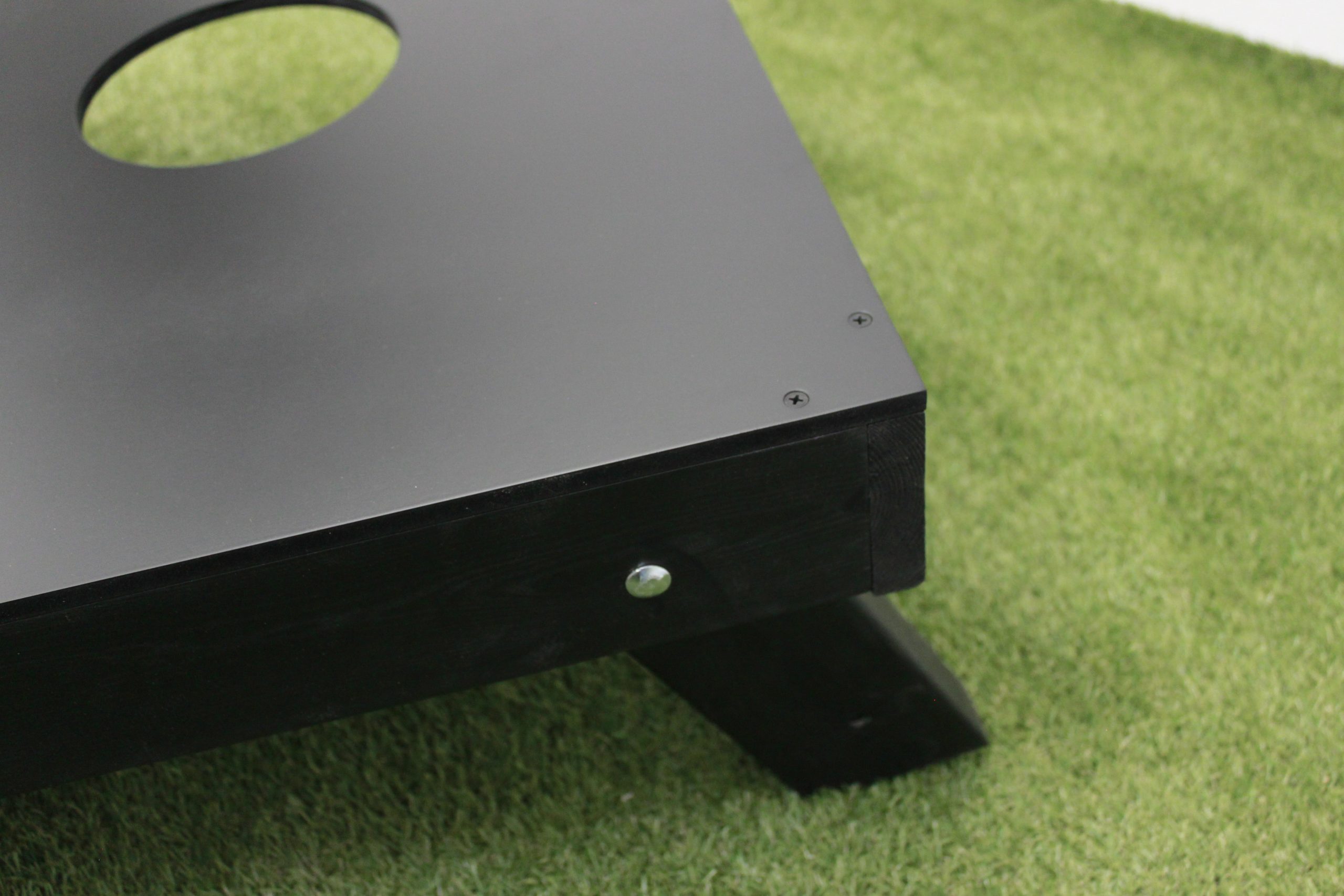 a cornboard game in black with the retractible leg in the extended position