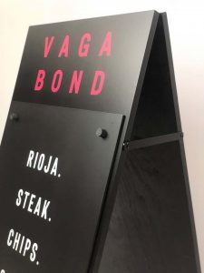 A black pavement sign made for Vagabond