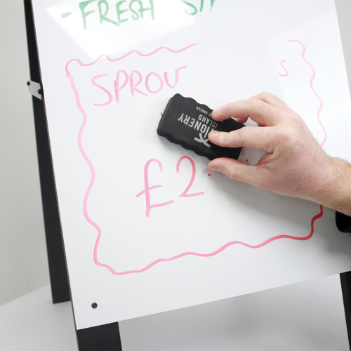 A person demonstrating the removal of whiteboard marker from a pavement sign