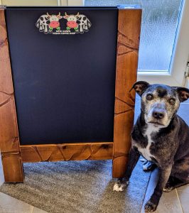 A wooden pavement sign with chalkboard boards that are reversible