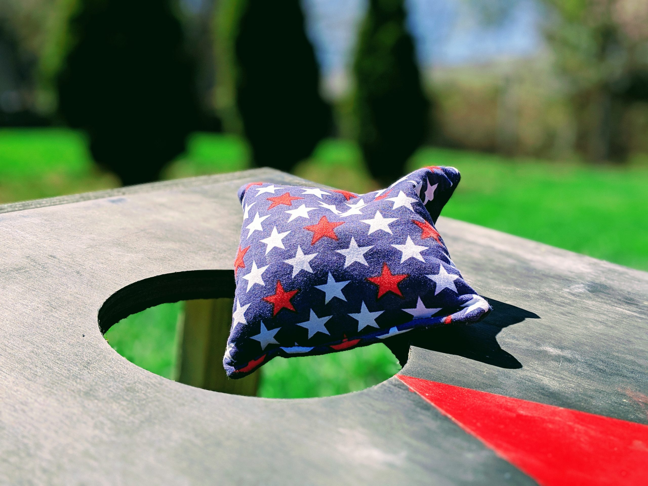 iStock 1144447440 scaled Wooden Cornhole Board with a beanbag being thrown at the hole