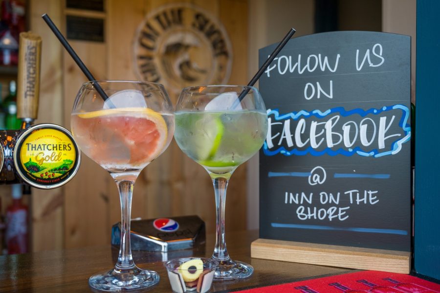 A tabletop table talker tombstone display next to 2 cocktail drinks